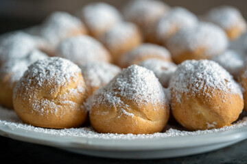 ready to eat on coffe time - small  cream puffs with powder sugar on a white plate