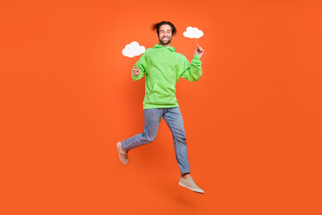Fototapeta na wymiar Full size photo of brunet young guy jump hold bubbles wear sweater jeans shoes isolated on orange background