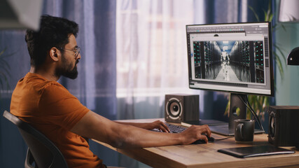 Indian male developer using computer to create and render 3D model of futuristic robot on computer...