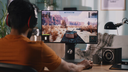 Bearded man controlling tank while playing videogame on modern computer in weekend at home
