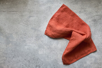 Folded linen napkin terracotta color on gray concrete table with copy space, top view - 472450188