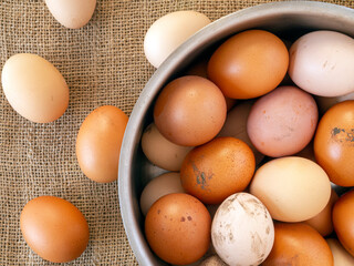 Brown farm eggs in a metal pan and on a beige burlap.