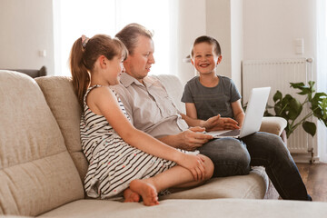 Vido call. Dad and children sit on the couch and call online grandparents or mom. Communication online, at a distance using the Internet.