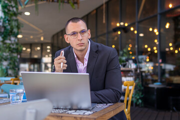 Young handsome businessman working on his laptop while sitting in a cafe