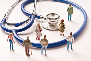 people figurines and stethoscope, public health system and medicare concept - obrazy, fototapety, plakaty