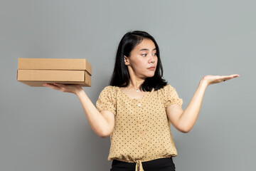Young woman comparing cardboard box in palm with one empty hand