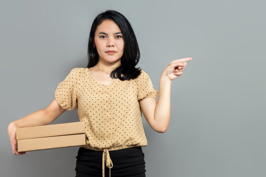 Serious Woman Holding Cardboard Box And Pointing To Empty Space