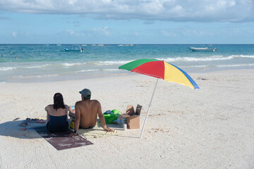 Couple on the beach under an umbrella in a sunny day