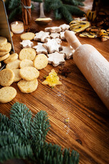 Various homemade christmas cookies and a dough roller on a wooden table. Vertical background with short depth of field for the sweet christmas baking.
