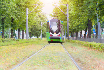 A tram running on rails surrounded by fresh green grass in city in Szczecin, Poland.