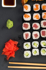 set of rolls and sauces on a black plate, top view