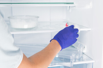 a worker washes the shelves inside the refrigerator with a sponge