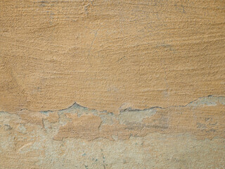 Pastel pale yellow wall. The surface is covered with scratches and cracks. The paint falls off.