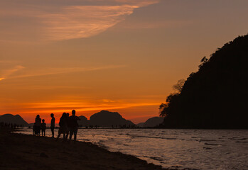 Silhouette of people watching sunset on Philippines island, El Nido. Scenic evening landscape on sunset. Tropical coast in night dusk. Amazing twilight at seaside.Tropical tourism. Evening mood.