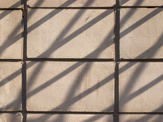 Wall view with gray tiles. A shadow from the grating falls on the surface.