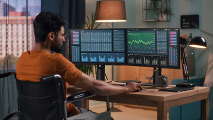 Anonymous man in orange t shirt analyzing graphs on computer monitors while trading on stock market online at home