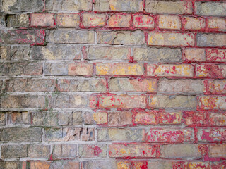 Gray brick wall with traces of red paint in the form of contours on the surface.