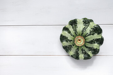 Green pattypan squash pumpkin on white wooden background close-up with copy space. Heathy organic food. Horizontal shot.