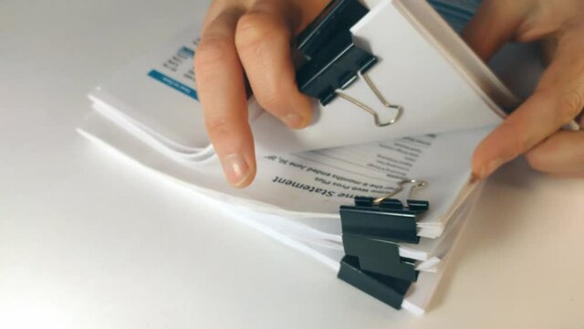 Front view of a Businessman hand searching documents files or information in Stack of financial report papers folder on work in office table
