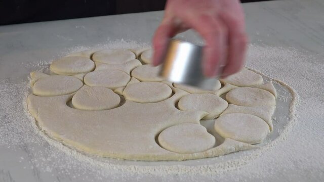 Woman cuts out dough circles with round mold for making sweet buns, dounuts.