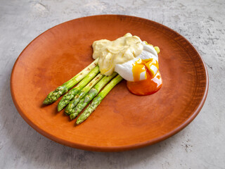 Grilled asparagus, poached egg and its parmesan coulis. From the cut egg, the yolk flows onto the plate.