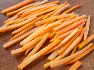 Side view of sliced ​​carrots. Closeup of julienne carrot on a wooden board.