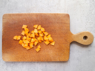 Wooden cutting board and sliced ​​juicy carrots. Paysanne cut.