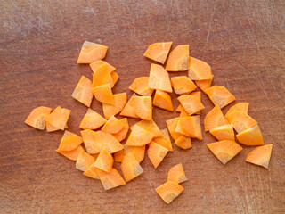 Closeup of chopped carrots on a wooden board. Paysanne cut.