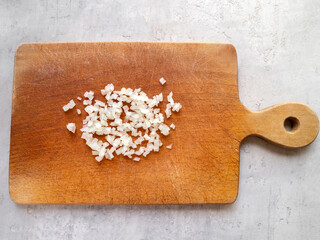 Top view of a wooden chopping board with chopped onions.