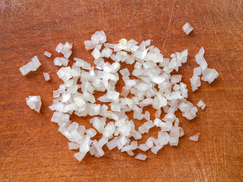 Top view of sliced ​​white onions on a brown wooden board.