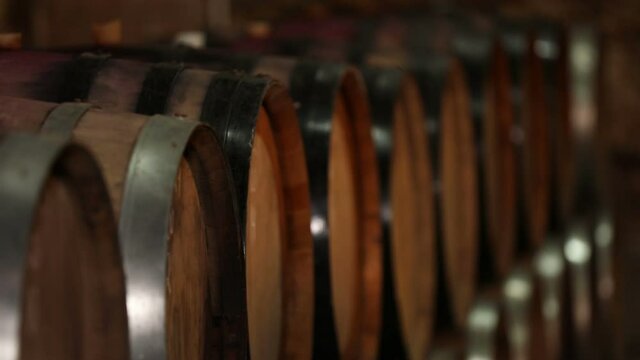 A Wine Cellar. Storage Room for Wine in Bottles and Barrels. Old wine in a dark underground vault. Wooden oak whiskey, wine, cognac, brandy or beer barrels. Bottles on wooden shelves.
