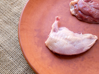 Side view of quail supreme breast on a brown clay plate.