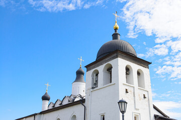 The black domes of the white church with golden crosses against the blue sky