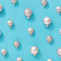 Creative pattern made of silver Christmas balls on pastel blue background. Minimal New Year concept. Cold winter holiday aesthetic.