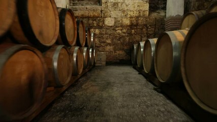 A Wine Cellar. Storage Room for Wine in Bottles and Barrels. Old wine in a dark underground vault. Wooden oak whiskey, wine, cognac, brandy or beer barrels. Bottles on wooden shelves.