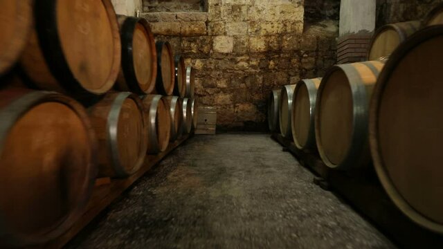 A Wine Cellar. Storage Room for Wine in Bottles and Barrels. Old wine in a dark underground vault. Wooden oak whiskey, wine, cognac, brandy or beer barrels. Bottles on wooden shelves.