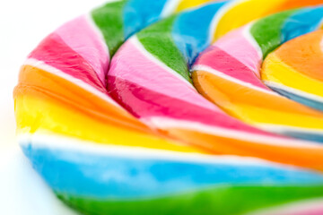 A macro photo of a sweet colorful lollipop in the shape of a spiral, isolated on a white background.