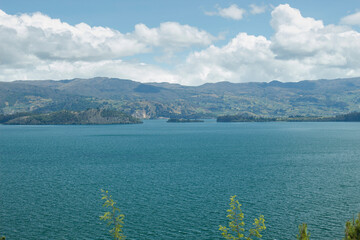 Beautiful summer scene of Blue Colombian Tota lake located in Boyaca, with andes mountains and cloudy blue sky at midday