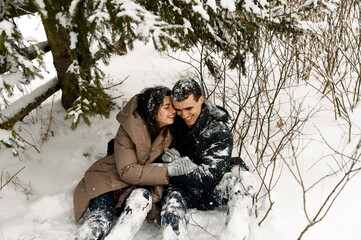 Loving couple in puffer jacket on a winter walk. Man and woman having fun in the frosty forest....