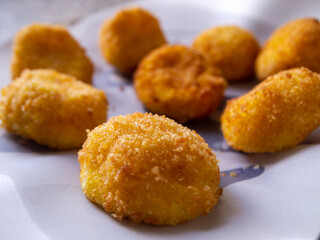 Side view of cheese croquettes on white paper. Delicious appetizer.