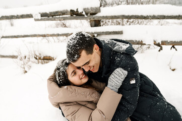 Loving couple in puffer jacket on a winter walk. Man and woman having fun in the frosty forest....