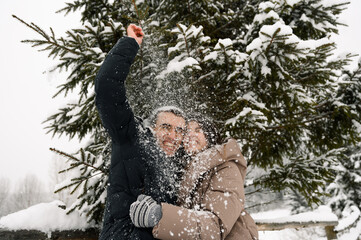 Loving couple in puffer jacket on a winter walk. Man and woman having fun in the frosty forest....
