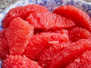 Lots of peeled grapefruit pieces on a plate.