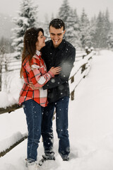 Fototapeta na wymiar Loving couple in shirt on a winter walk. Man and woman having fun in the frosty forest. Romantic date in winter time.Christmas mood of a young family.Winter lovestory