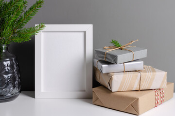 Photo or poster frame mockup with decorated christmas gift boxes over grey wall interior