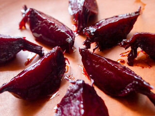 Pieces of baked caramelized beetroot on a brown earthenware plate.