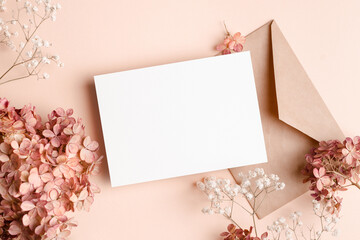 Greeting or invitation card mockup with envelope, hydrangea and gypsophila flowers decorations.