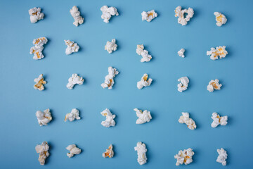 Fototapeta na wymiar Popcorn lay out on blue background, top view. Food pattern