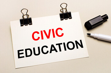 On a light background, a black open marker and on black clips a white sheet of paper with the text CIVIC EDUCATION