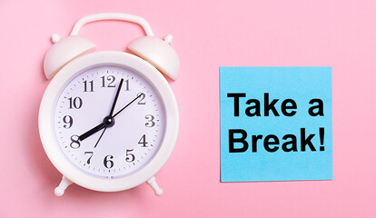 On a light pink background, a white alarm clock and a blue sheet of paper with the text TAKE A BREAK